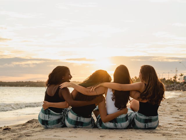 4 women hugging each other on a sunset beach