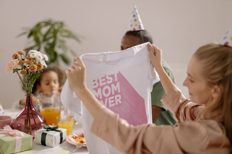 women opens a gift with best mom ever as a gift from her family